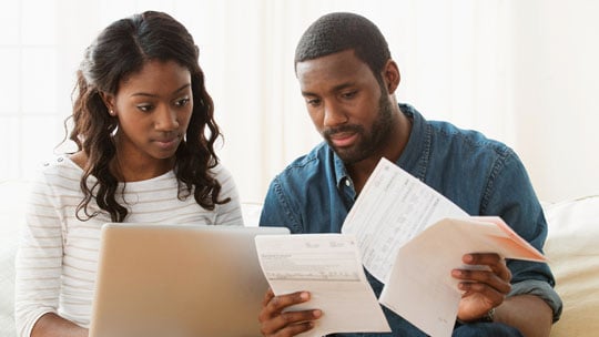 Woman and man review multiple credit card bills. 